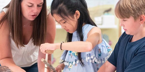 museum volunteer showing artifact to young children