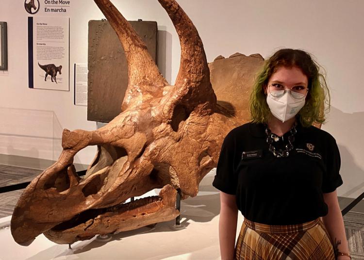 Emily Howard standing in front of a triceratops skull in Paleontology Hall