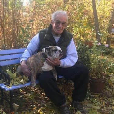 Dr Romig sitting on park bench with his dog