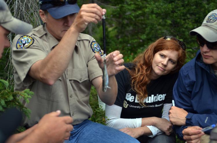 Jessica Metcalf watching Harry Crockett weigh a cutthroat trout.