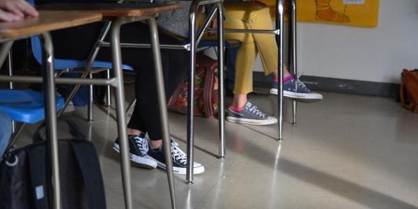 Feet and legs of students sitting at desks in a classroom