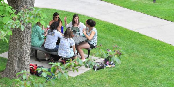 Students sitting at table outside the School of Education