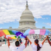 People wave LGBTQ+ flags in front of the U.S. Capitol Building