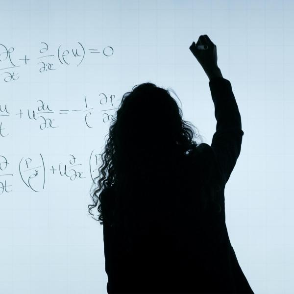 person writing math equations on blackboard