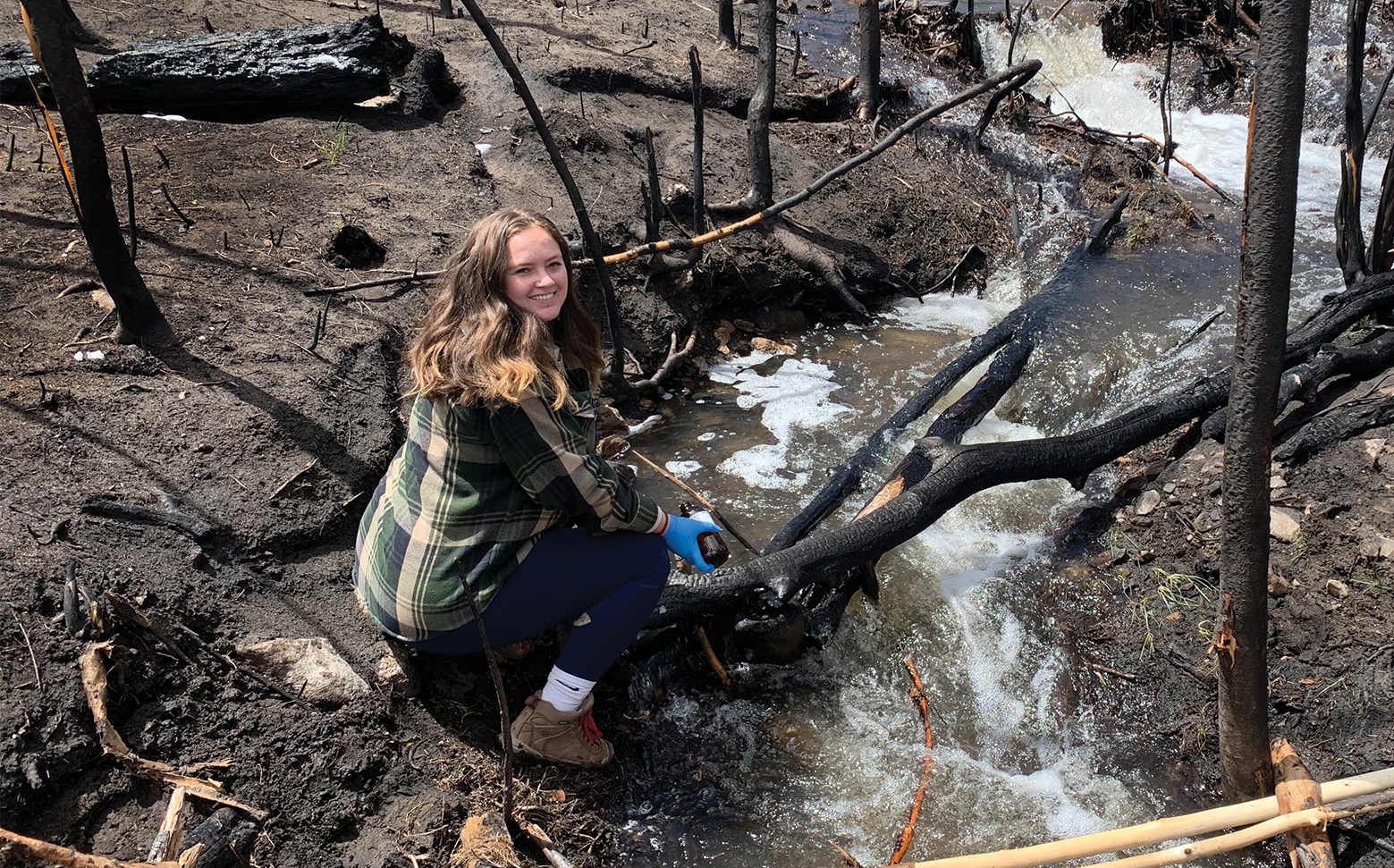 A researcher from Rosario-Ortiz’s lab collect water samples from a creek running through a burn area. 