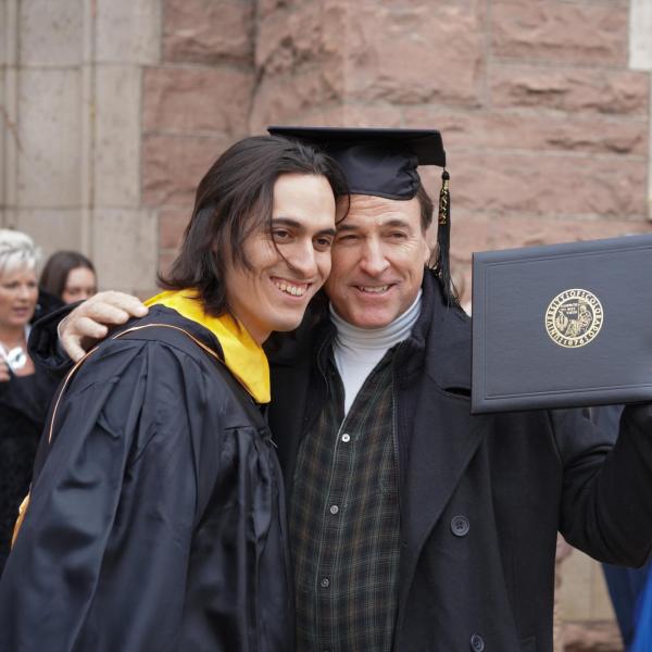 Grad posing for picture with parent