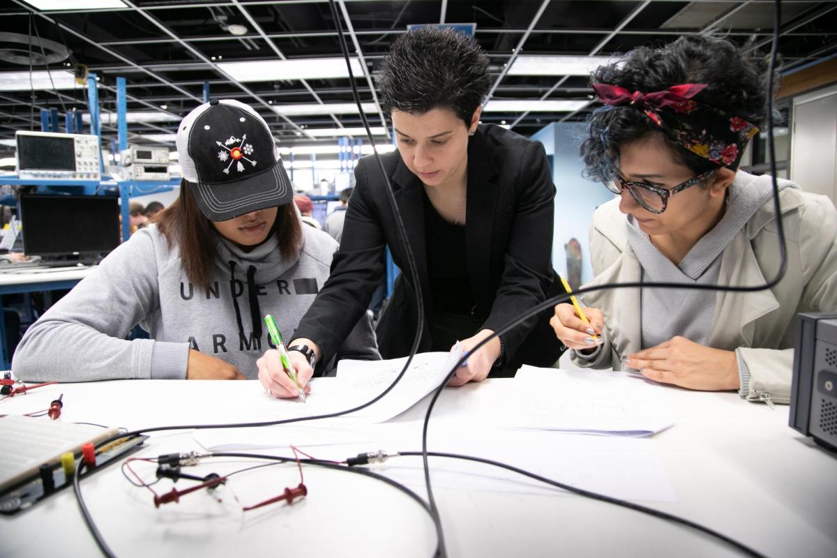 A faculty member helps two students with an assignment during a lab session