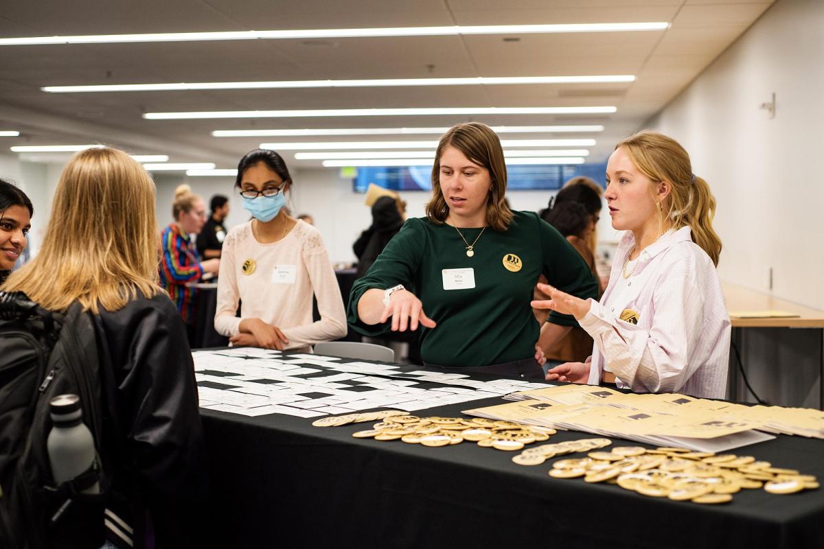 Three staff members work a check-in table for a college event