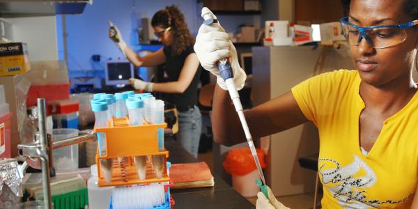 Person in yellow shirt holds pipet