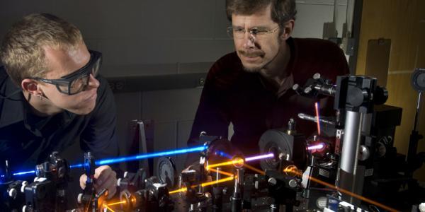 Two people stare at a maze of lasers