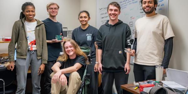 A six-person teams shows off an assistive mobility device in the ECEE capstone lab