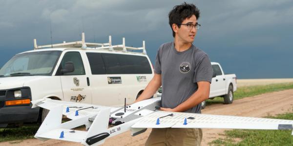 Student in the field holding a drone 