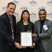 Lucy Pao accepting her award with two presenters 