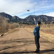 Alex Lubar reads the anemometer measurements while Wilson Hughes flies a drone at CU Boulder South Campus.