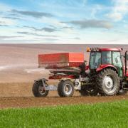 An agricultural tractor spreading fertilizer.