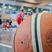 A basketball with a court and players in the background. 