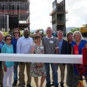 A group of officials standing with the final beam.