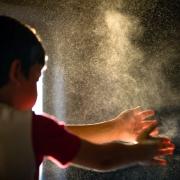 A child spraying something into the air by clapping.