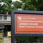 Shot of the Lesser House red sign with building behind it