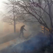 A person fighting a fire near a house