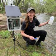 Emily Bedell collecting a sample from a river