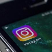 The Instagram icon is displayed on a smartphone screen. 