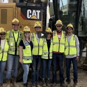 Kiewit Design-Build Scholars at a job site with video play button graphic
