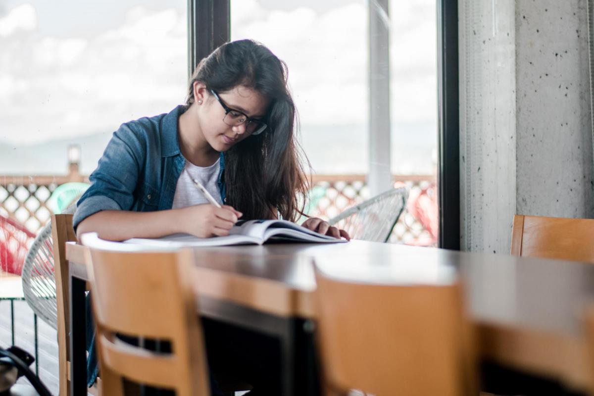 Female student studying at table with books