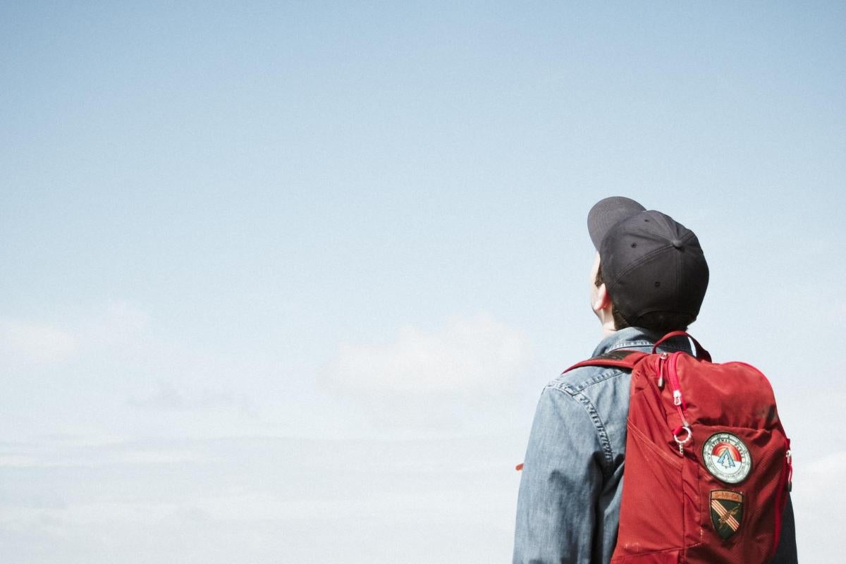 student with backpack looking into sky