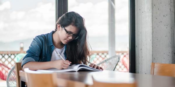 Female student studying at table with books