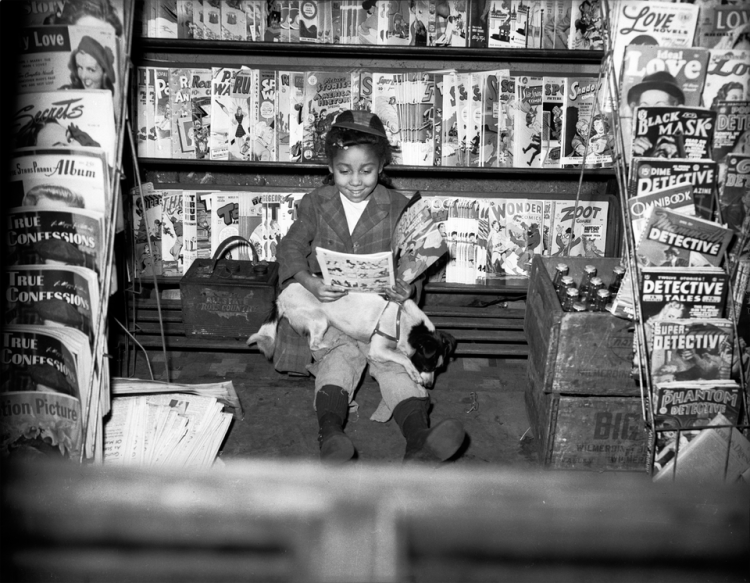 A young girl reading a magazine outside