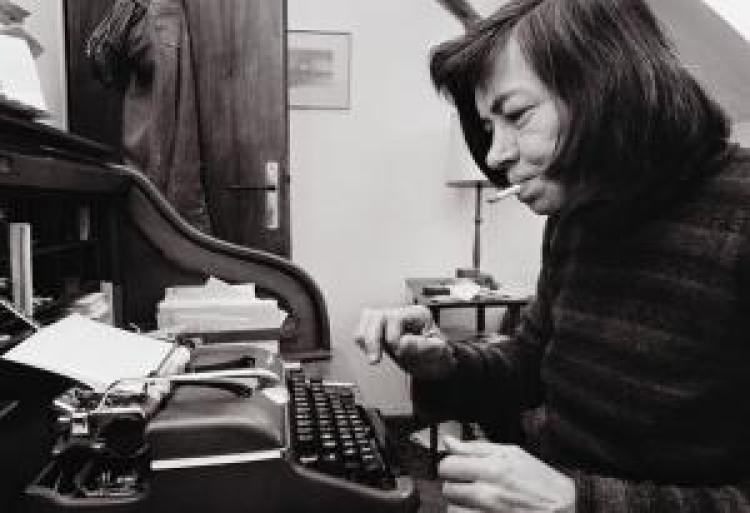 A woman is sitting at a desk in front of a typewriter