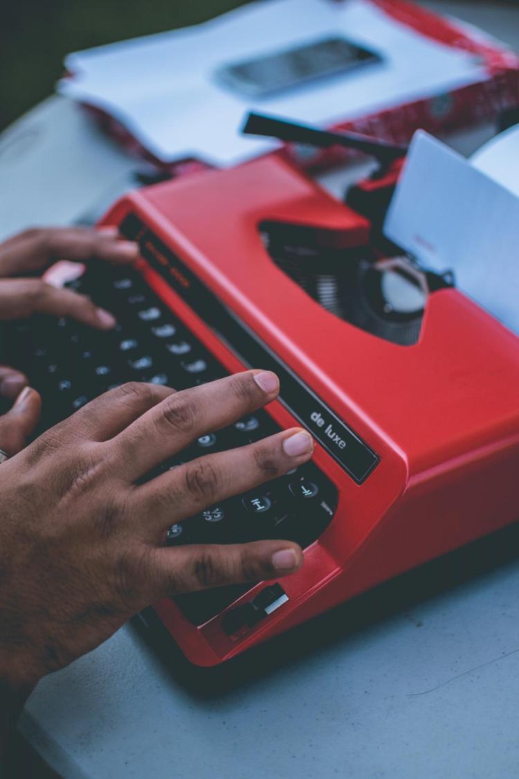A person typing on a red typewriter