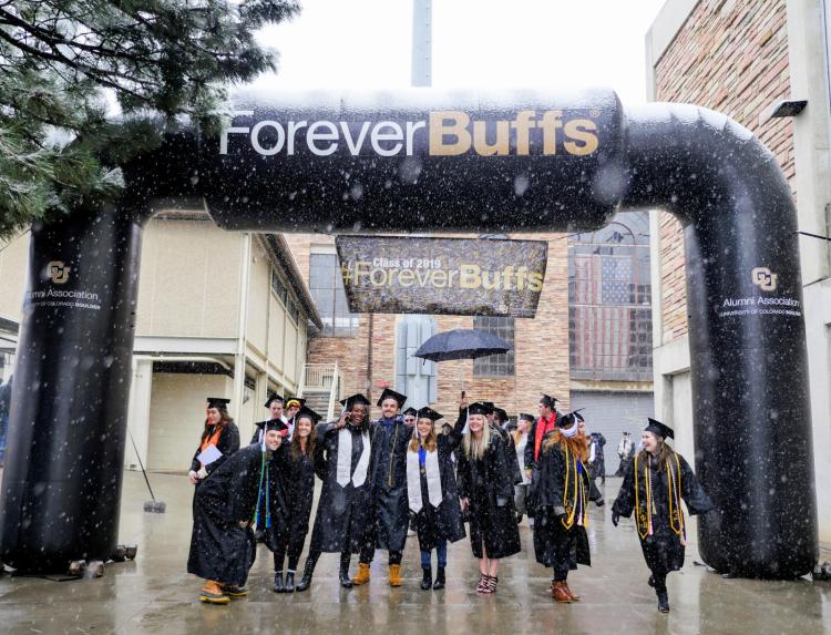 A group of CU graduates under a Forever Buffs insignia 