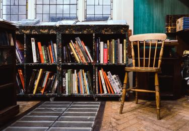 A wooden chair next to a bookshelf
