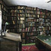 A room with a desk and stacks of books