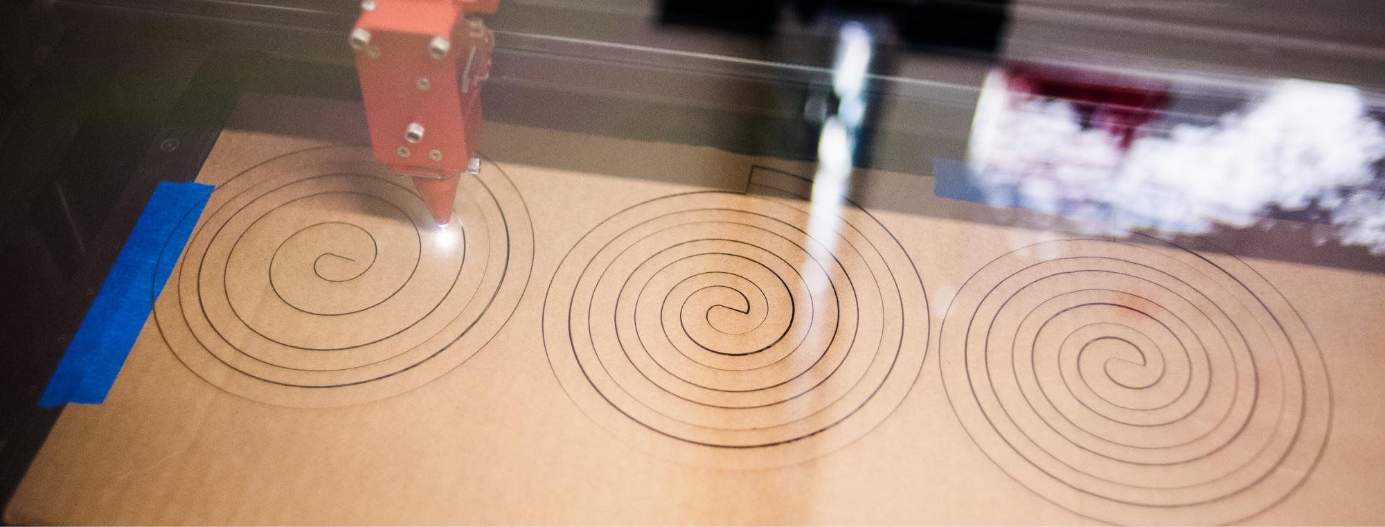 Laser cutter cutting spirals in cardboard.
