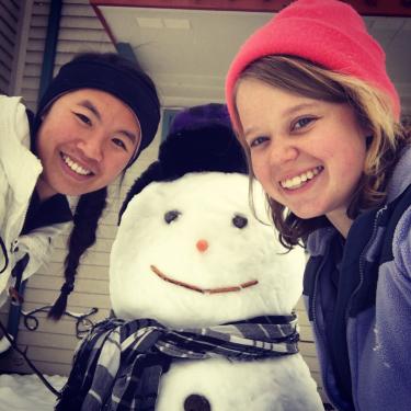 Elyse and her friend pose next to a snowman.