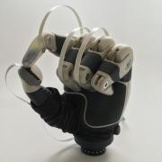 A curled up prosthetic hand with the pointer finger touching the thumb.