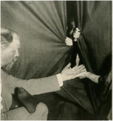  A flashlight photograph of Eva producing ectoplasm from the medium’s cabinet. Schrenck-Notzing appears on the left. Image courtesy of Hathi Trust.