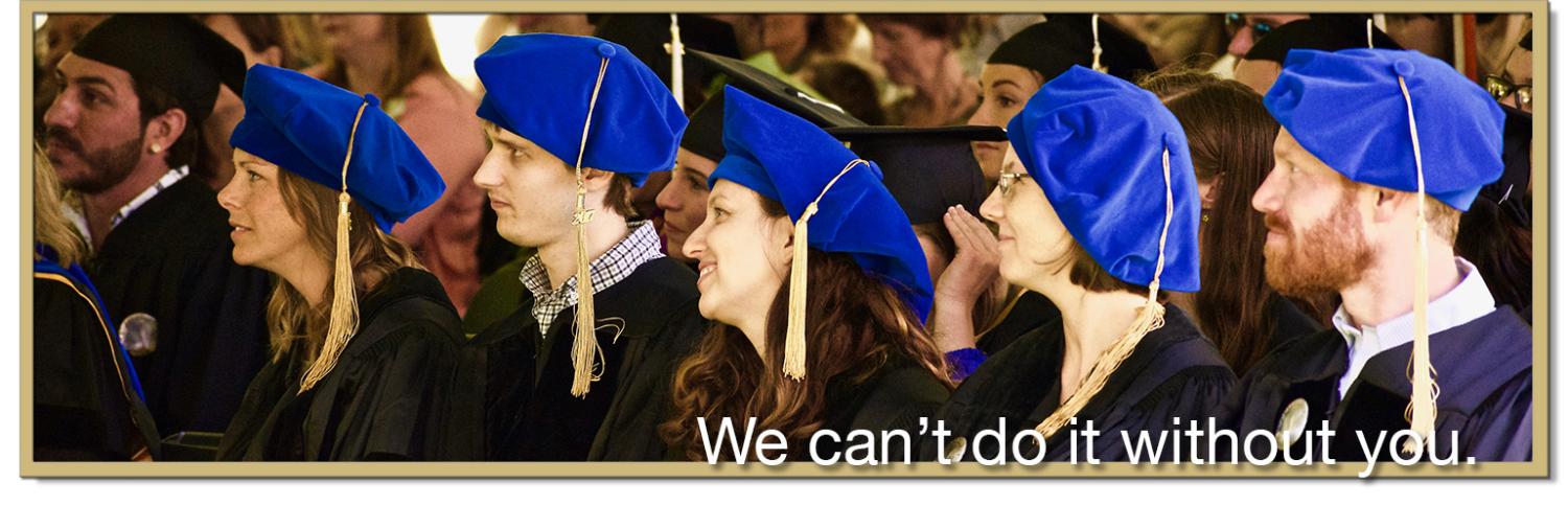 Advanced degree students in caps and gowns watch commencement speeches