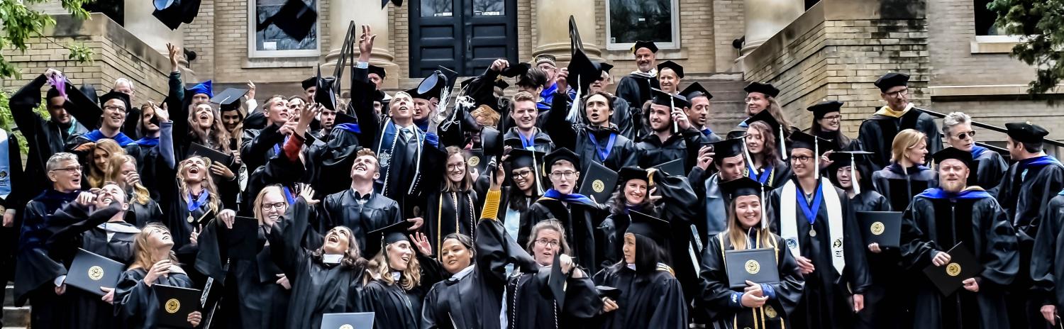 Commencement group photo of student tossing their mortarboards 