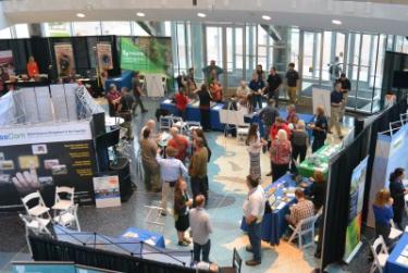 Wide shot of people milling around amongst kiosks and conference booths.