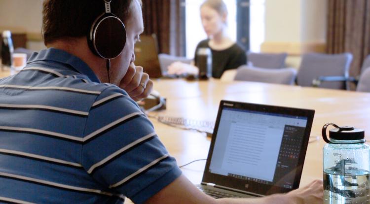 Graduate student with headphones concentrated on laptop