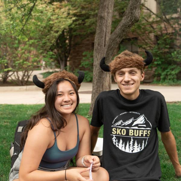 Photo of two students sitting together on farrand field.