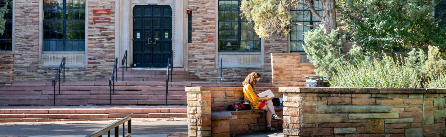 Photo of a student reading quietly in a nook on campus by themselves.