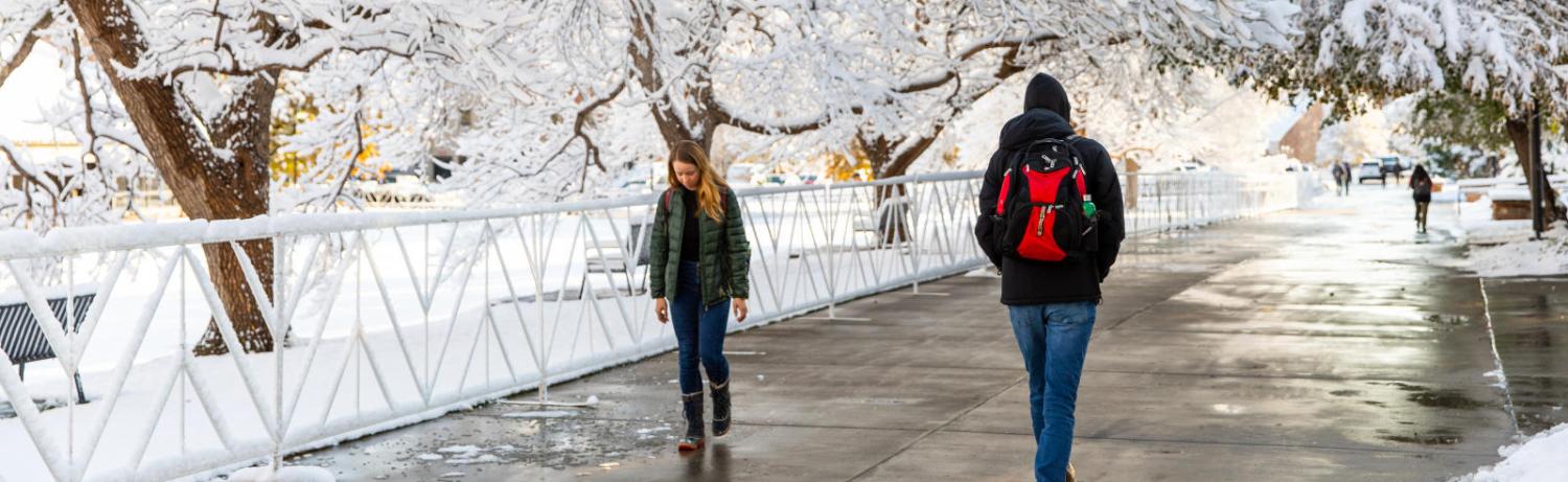 Two students walking on campus on a snowy day.