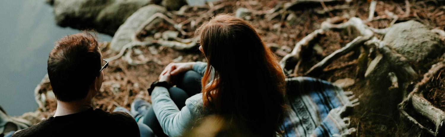 Two friends sitting in the woods, talking.