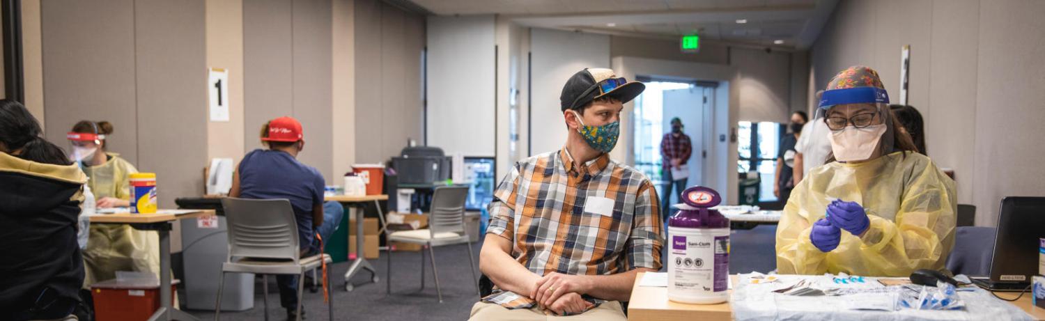 Man sitting at the COVID-19 vaccination clinic at CU Boulder.