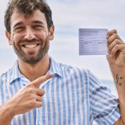 Photo of a young man holding up his vaccination card.
